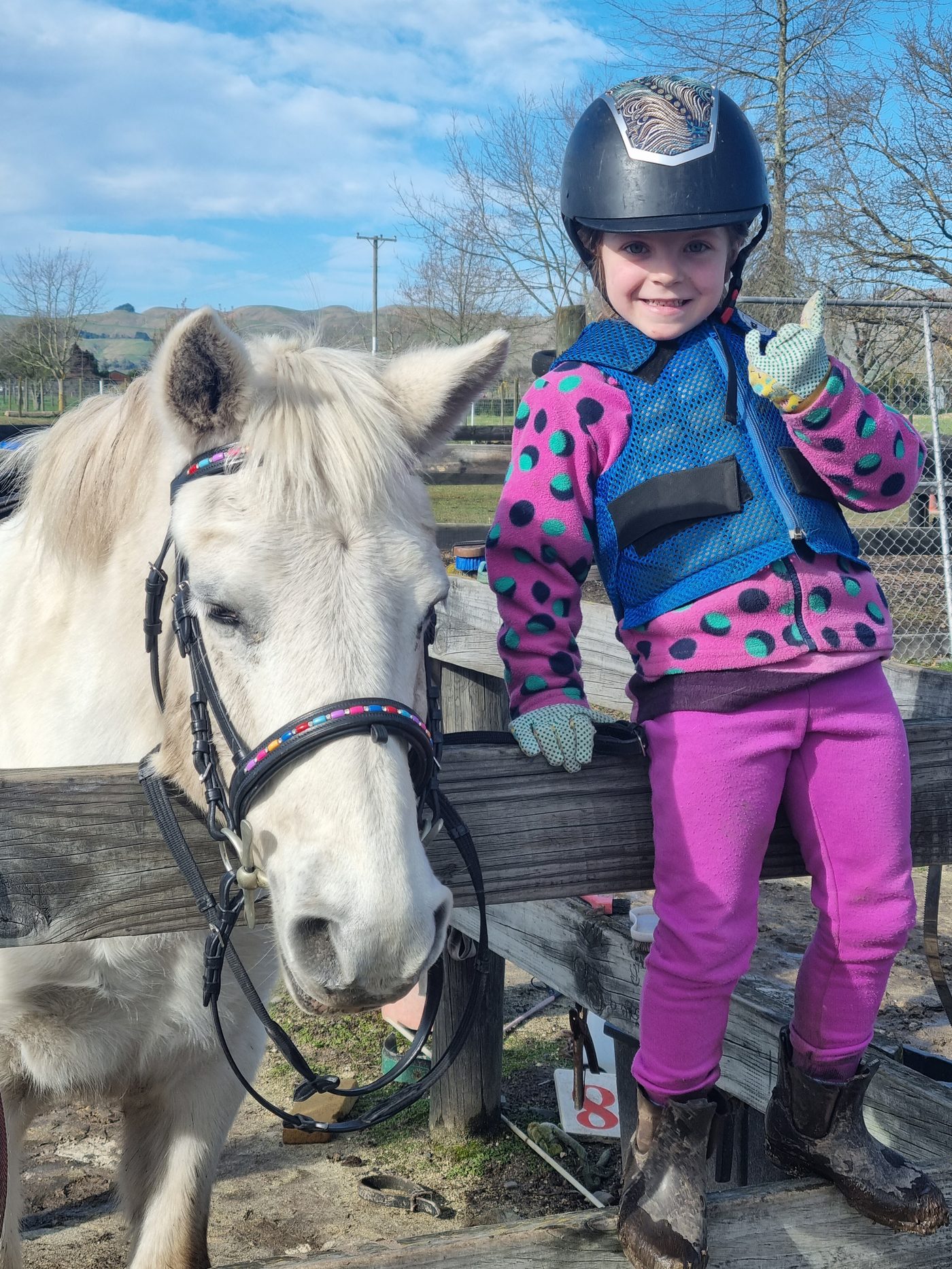 A young rider giving a thumbs-up next to her pony at Acreswild